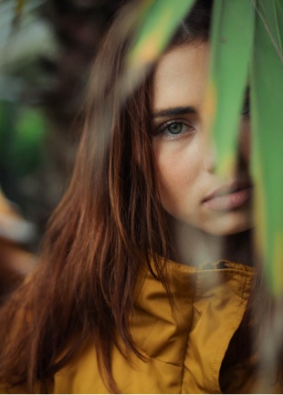 a portrait of Willow behind a glance in a yellow jacket 